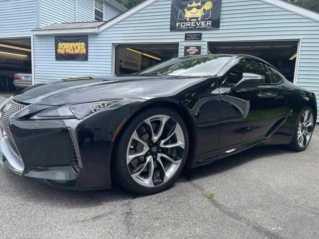 The black Lexus LC, protected with ceramic coatings, is parked in front of a garage
